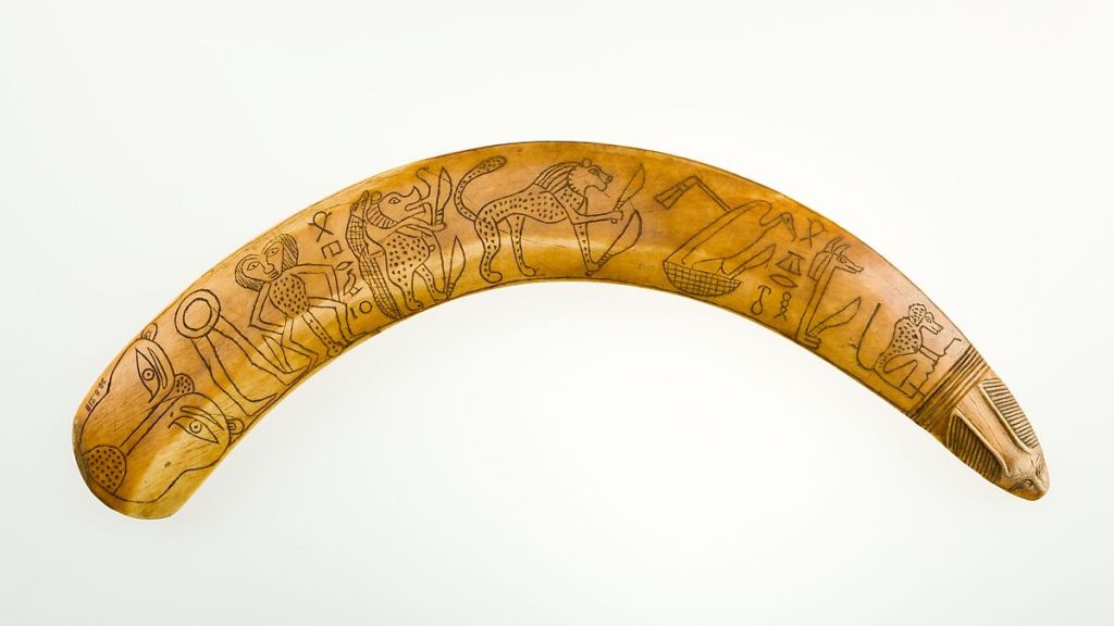 A photo of an ancient Egyptian boomerang-shaped wand, inscribed with demon figures. 