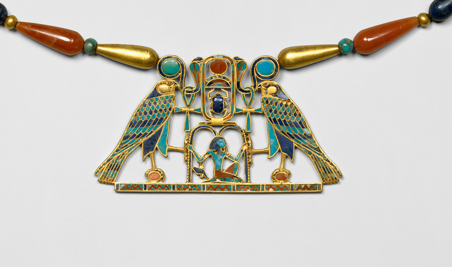 A photo of an Egyptian pectoral mounted on a necklace. The pectoral includes two falcons before the god Heh, and is made of many precious stones, including turquoise, lapis, and carnelian, as well as gold. 